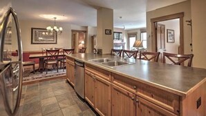 A modern kitchen with wooden cabinets, a stainless steel refrigerator, and a central island with a sink. - Beautiful 3 Bedroom Mountain Condo in River Run Village With Hot Tub Access and Walking Distance to the Gondola (Keystone)