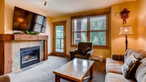 A cozy living room with a fireplace, a television, a sofa, and a coffee table. - Beautiful 3 Bedroom Mountain Condo in River Run Village With Hot Tub Access and Walking Distance to the Gondola (Keystone)