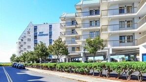 A multi-story hotel with balconies and a parking area. - LAST DATES! Bay Sunset Getaway • Pool • 2BR/2BA • Free Linens (Ocean City)