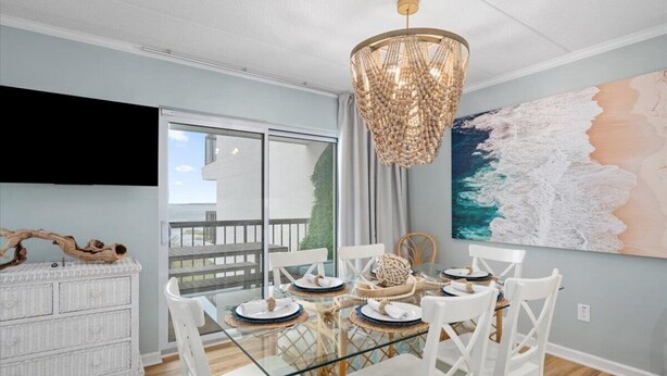 A dining area with a glass table, white chairs, and a chandelier. - LAST DATES! Bay Sunset Getaway • Pool • 2BR/2BA • Free Linens (Ocean City)