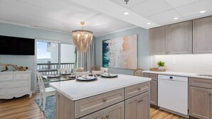 A modern kitchen with a large island, wooden cabinets, and a view to the outside. - LAST DATES! Bay Sunset Getaway • Pool • 2BR/2BA • Free Linens (Ocean City)