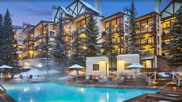 Un hôtel doté d'une piscine, de chaises longues et d'un espace extérieur enneigé.
