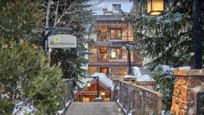 L’entrée d’un hôtel, avec une enseigne indiquant « Montaneros », un escalier en bois et un paysage enneigé.