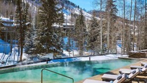 A pool area with lounge chairs and a view of snow-covered mountains.