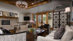 A modern living room with a fireplace, comfortable seating, and a large window offering a view of the outdoors. - 4 Bedroom Condo in Lionshead at Boutique Resort Within Walking Distance to the Eagle Bahn Gondola (Vail)