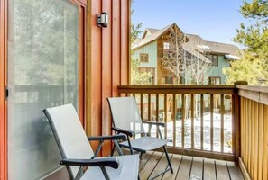 Guests can enjoy the deck with two lounge chairs and a glass door leading to a view of the surrounding area.