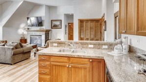 A modern kitchen with wooden cabinets, granite countertops, and a built-in sink. - Downtown Breckenridge 2 Bedroom Condo - Steps to Lifts and Main Street (Breckenridge)