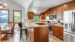 A modern kitchen with wooden cabinets, stainless steel appliances, a large island, and a view of the outdoors. - 3 Bedroom Mountain Vacation Rental on Historic Downtown Main Street Within Walking Distance to Peak 9 Gondola (Breckenridge)