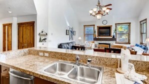 A kitchen with granite countertops, stainless steel sinks, and a chandelier. - 3 Bedroom Mountain Vacation Rental on Historic Downtown Main Street Within Walking Distance to Peak 9 Gondola (Breckenridge)