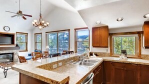 A spacious kitchen with a large island, wooden cabinets, and a view of the outdoors. - 3 Bedroom Mountain Vacation Rental on Historic Downtown Main Street Within Walking Distance to Peak 9 Gondola (Breckenridge)