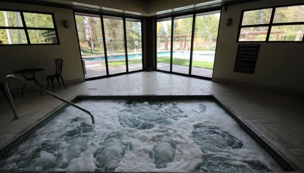 Un bain à remous avec vue sur une piscine et les arbres environnants.