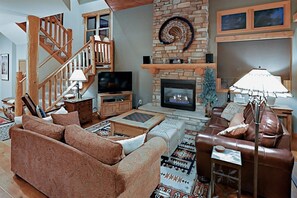 A cozy living room with a fireplace, a television, a sofa, and a leather armchair. - Family-friendly 3 Bedroom Vacation Rental in West Keystone Resort Along the Snake River With Pool and Hot Tub (Keystone)