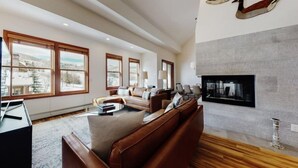 A spacious living room with a fireplace, large windows, and a modern design. - Premier Ski in, Ski-out 3 Bedroom Condo With Spectacular Views, Heated Outdoor Pool and Hot Tub, Short Walk to Village (Snowmass Village)