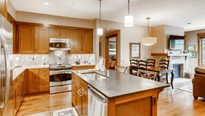 A modern kitchen with wooden cabinets, stainless steel appliances, and a central island. - Luxury 2 Bedroom Mountain Vacation Residence With Hot Tub, Pool, and Easy Access to Ski Slopes (Breckenridge)
