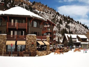 A lodge with multiple balconies and stone pillars, surrounded by snow-covered mountains.