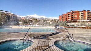 Een zwembadgedeelte met meerdere jacuzzi's en een uitzicht op besneeuwde bergen op de achtergrond.