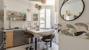 Una cucina moderna con zona pranzo, elettrodomestici in acciaio inossidabile e un grande specchio.