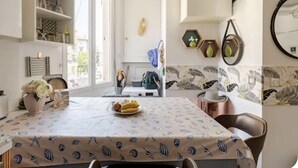 Un'area pranzo con un tavolo ricoperto da una tovaglia a motivi di pesce, circondato da sedie.