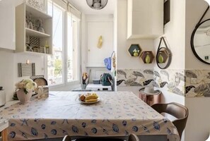 Een eethoek met een tafel, bedekt met een tafelkleed met een vispatroon, omringd door stoelen.