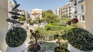 Un balcone con piante in vaso e vista su una strada residenziale, con edifici e vegetazione.
