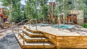 A spa area with two hot tubs, stone steps, and a metal railing.