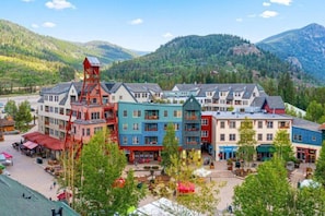A multi-story hotel with a central courtyard, surrounded by mountains and trees.