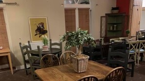 A dining area with a wooden table and chairs, a potted plant, and a painting on the wall. - The Barrington Arms Hotel (Swindon)
