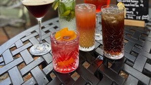 A table with four drinks and a menu board in an outdoor setting. - The Barrington Arms Hotel (Swindon)
