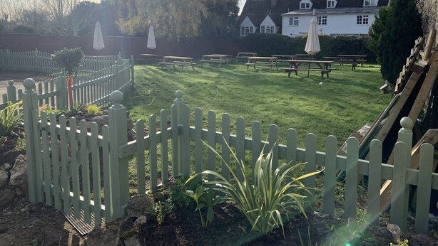 A well-maintained garden with picnic tables and a white picket fence. - The Barrington Arms Hotel (Swindon)