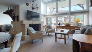 A spacious living room with a fireplace, comfortable seating, and large windows offering a view of the outdoors. - 3 Bedroom Condo at Boutique Resort With Hot Tub Access and Within Walking Distance to the Eagle Bahn Gondola (Vail)