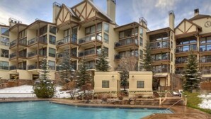 A multi-story hotel with balconies, a swimming pool, and snow on the ground. - 3 Bedroom Condo at Boutique Resort With Hot Tub Access and Within Walking Distance to the Eagle Bahn Gondola (Vail)