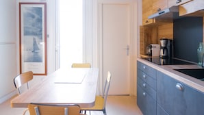 Eine moderne Küche mit einem Holztisch und Stühlen, einer Kaffeemaschine und Blick ins Freie.