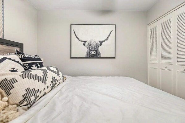 Un dormitorio con cama, una obra de arte enmarcada de una cabeza de toro y un armario.