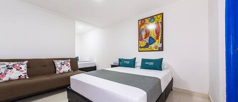 A hotel room with a bed, a sofa, and a painting on the wall.