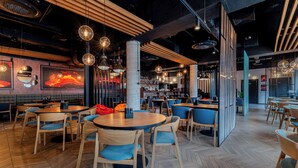 A modern restaurant interior with round tables, blue chairs, and hanging pendant lights. - Seaside Apartamenty Kasprowicza (Kolobrzeg)