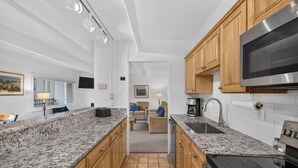 A kitchen with granite countertops, wooden cabinets, a stainless steel microwave, and a black stove.