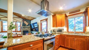 Une cuisine avec des meubles en bois, une cuisinière en acier inoxydable et une cheminée en pierre.