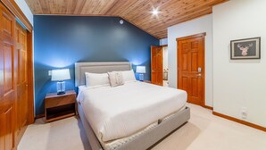 Une chambre avec un grand lit, un plafond en bois et un mur d’accent bleu.