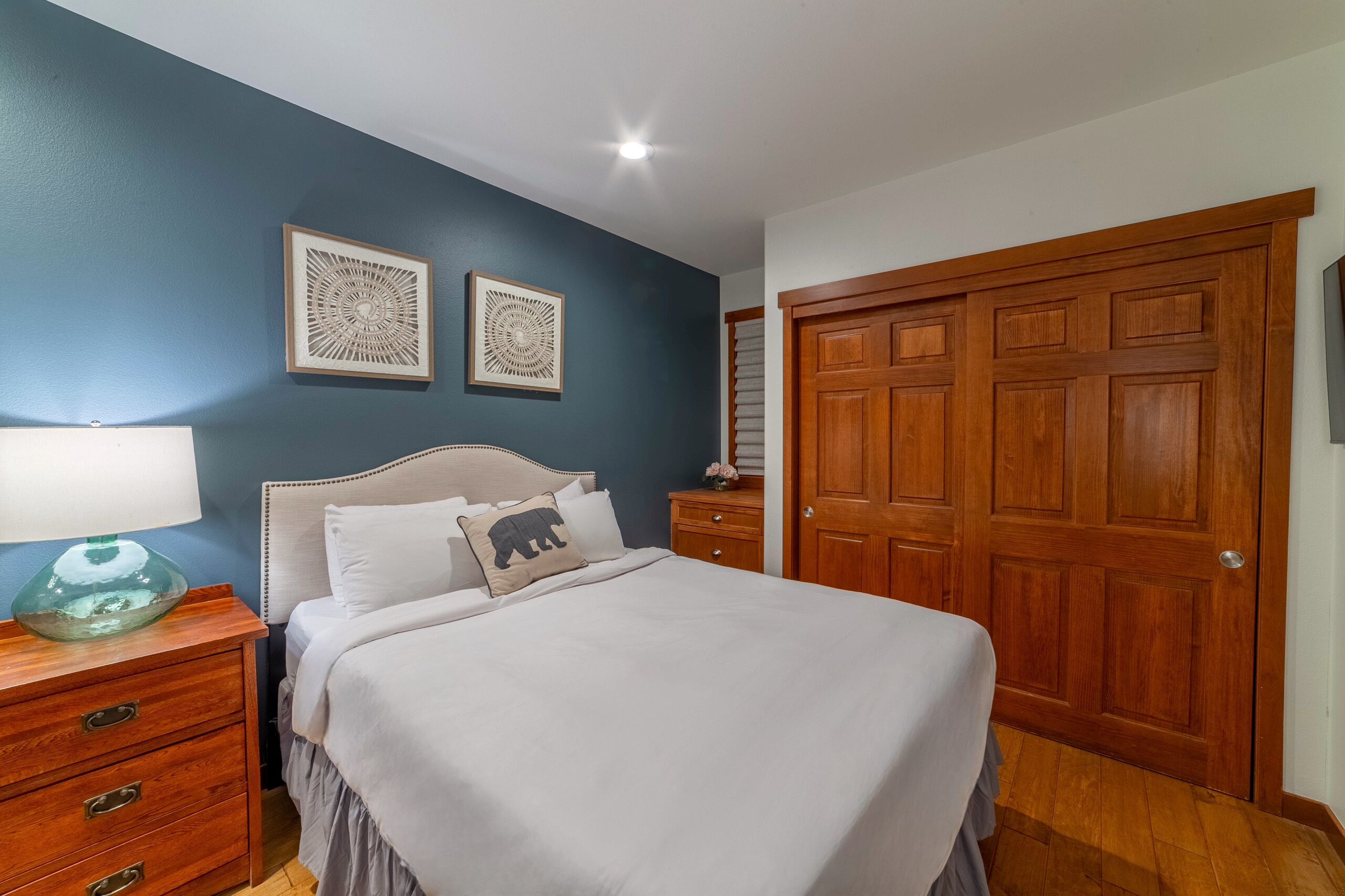 A bedroom with a bed, a nightstand, a dresser, and a wooden door.