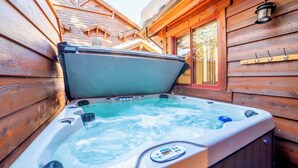 Un bain à remous dans un chalet en bois, avec une façade en bois et une fenêtre.