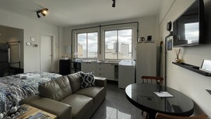 Una camera d'albergo compatta con un letto, una poltrona letto, un piccolo tavolo da pranzo e una TV.