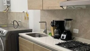 Una cucina moderna con lavatrice e asciugatrice integrate, piano cottura a gas e un bancone con un frullatore.