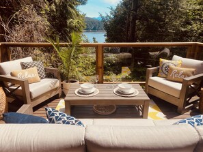 Una terrazza con due divani, un tavolino da caffè e vista su un lago.