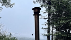A hot tub with a wooden deck and metal structure, surrounded by trees and a misty background. - #Slowtravel+Wellness~woodfired hot tub, cold plunge, sauna, forestbathing, beach (Halfmoon Bay)
