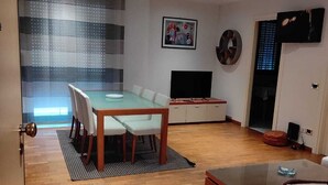 Ein modernes Wohnzimmer mit Essbereich, einem Flachbildfernseher und einer Couch.