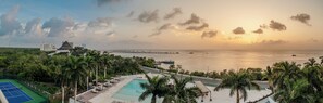 A resort with a swimming pool, tennis court, and a view of the ocean at sunset. - CASA MERMAID - Newly Redecorated Condo On The 6th Floor (Cozumel)