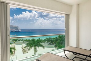 A balcony with a view of a cruise ship, beach, and palm trees. - CASA MERMAID - Newly Redecorated Condo On The 6th Floor (Cozumel)