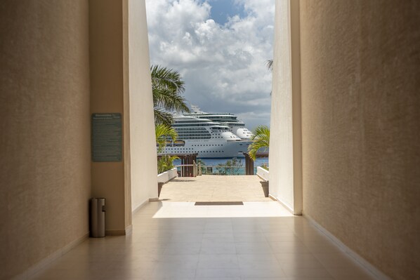 Un pasillo que da a un balcón con vista a un crucero llamado 'BRILLANCE THE SEAS' anclado en un puerto.