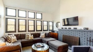 A living room with a sectional sofa, a round coffee table, and a fireplace. - Premier Ski in, Ski-out 1 Bedroom Condo With Spectacular Views, Heated Outdoor Pool and Hot Tub, Short Walk to Village (Snowmass Village)