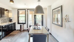 A modern kitchen with dark cabinetry, a built-in oven, and a large window. - Premier Ski in, Ski-out 1 Bedroom Condo With Spectacular Views, Heated Outdoor Pool and Hot Tub, Short Walk to Village (Snowmass Village)